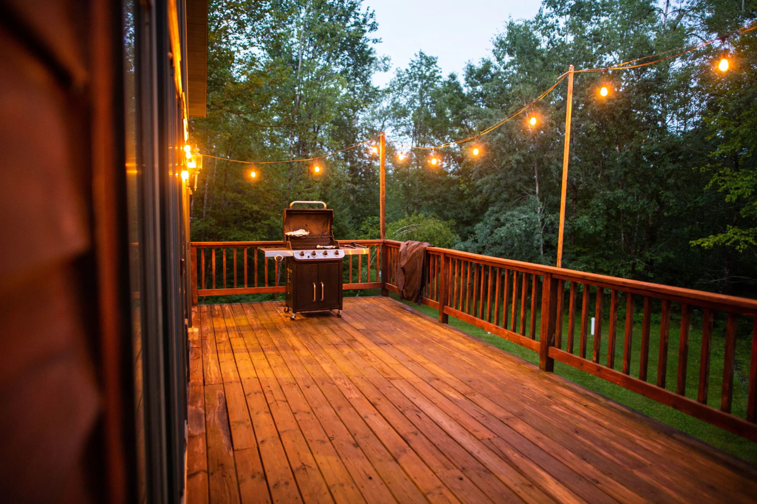 Wooden porch with string lights and grill